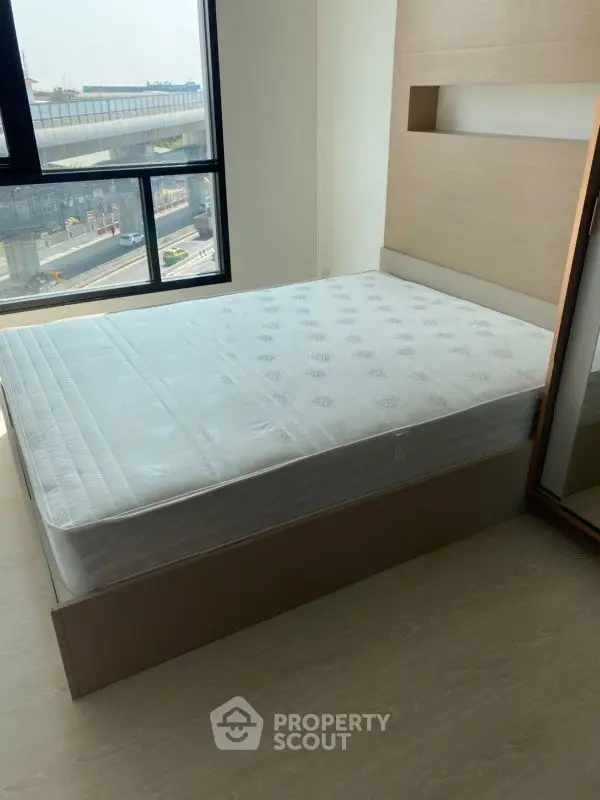 Luxurious bedroom with large windows offering stunning city view, modern decor, and ample natural light.