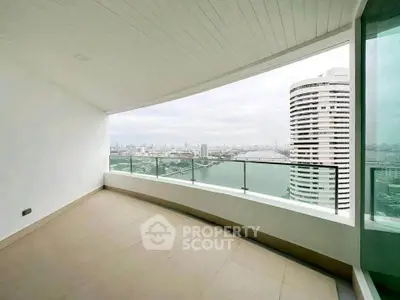 Spacious balcony with stunning city and river views in modern high-rise apartment.