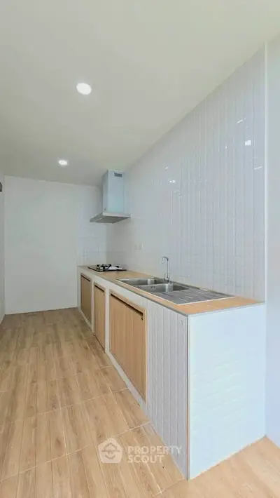 Modern kitchen with sleek wooden cabinets and tiled backsplash, featuring a gas stove and stainless steel sink.