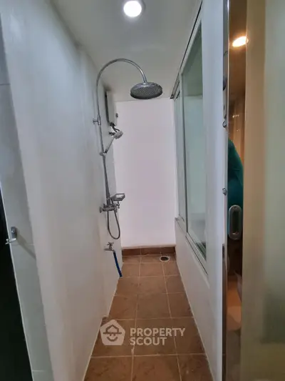 Compact bathroom with modern shower and glass partition in a sleek real estate property.