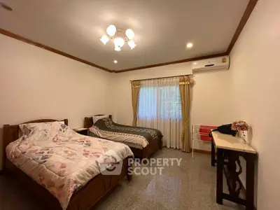 Spacious bedroom with twin beds and elegant decor in a cozy home setting.
