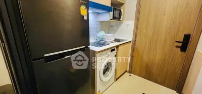 Compact kitchen with modern appliances including fridge, washing machine, and microwave in cozy apartment.