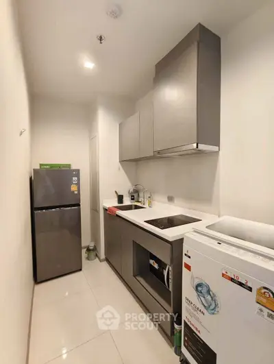 Modern kitchen with sleek cabinetry, washing machine, and refrigerator in a compact layout.