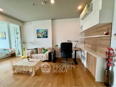 Modern living room with stylish decor and workspace, featuring wooden floors and cozy seating area.