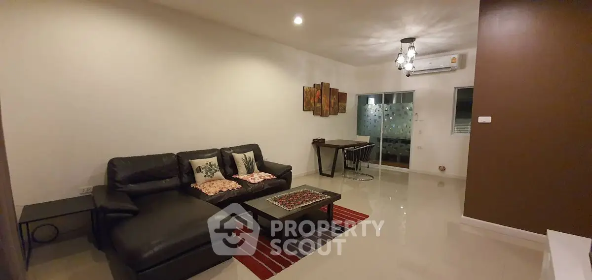 Modern living room with leather sofa and dining area, featuring stylish decor and air conditioning.
