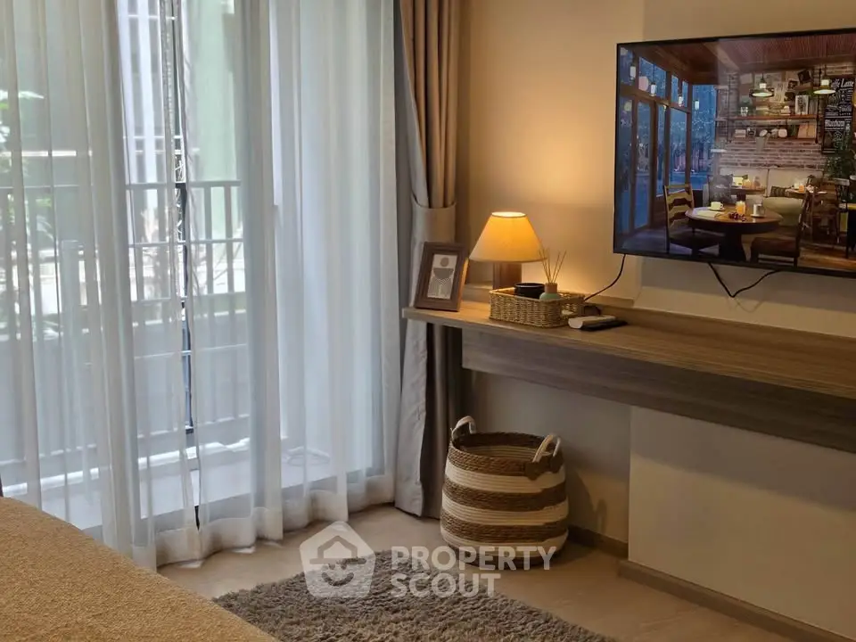 Cozy living room with modern decor and balcony view, featuring a wall-mounted TV and stylish lighting.
