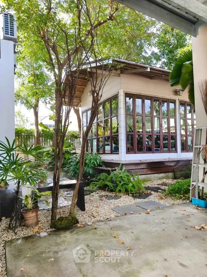 Charming garden view with modern glass-walled building and lush greenery