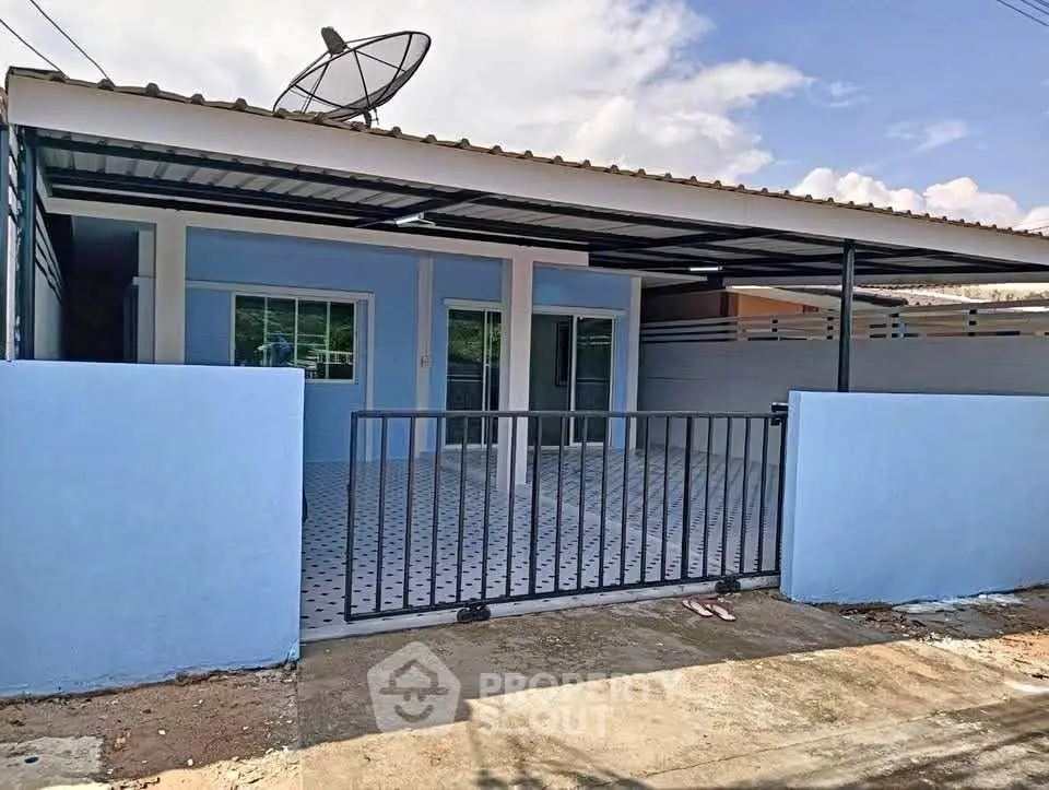 Charming single-story blue house with gated driveway and satellite dish, perfect for modern living.