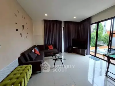 Spacious living room with modern decor and pool view, featuring a stylish sofa and glass coffee table.