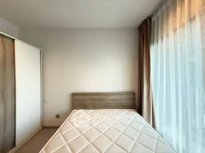Bright and cozy bedroom with large window and modern wardrobe, perfect for relaxation.
