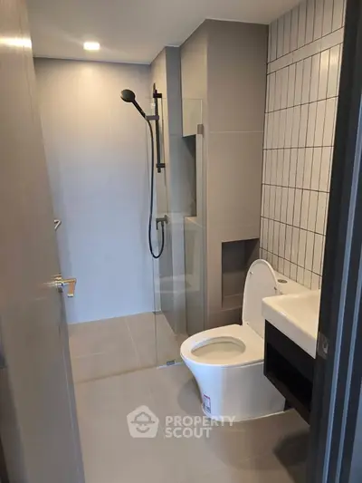Modern bathroom with sleek design, featuring a glass shower enclosure and contemporary fixtures.