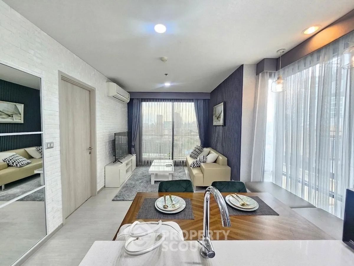 Modern living room with open kitchen, featuring sleek design and city view.