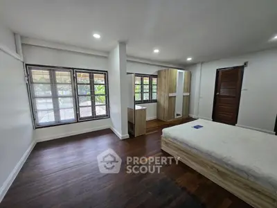 Spacious bedroom with large windows and wooden flooring in a modern home.