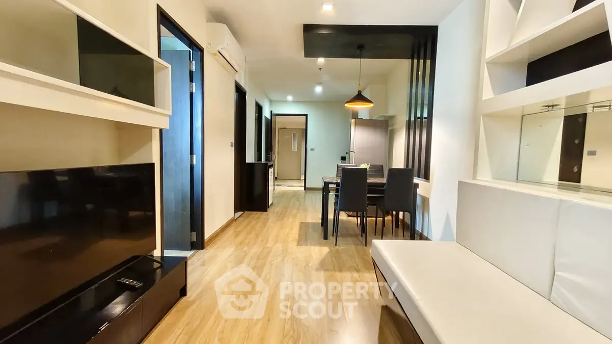 Modern open-plan living and dining area with sleek furnishings and wooden flooring.