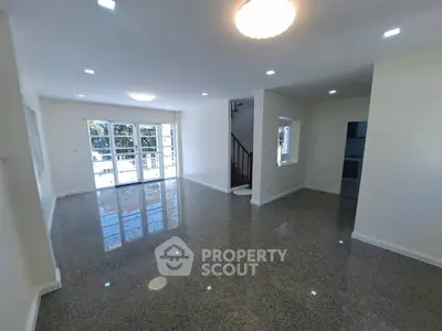 Spacious modern living room with glossy flooring and ample natural light.