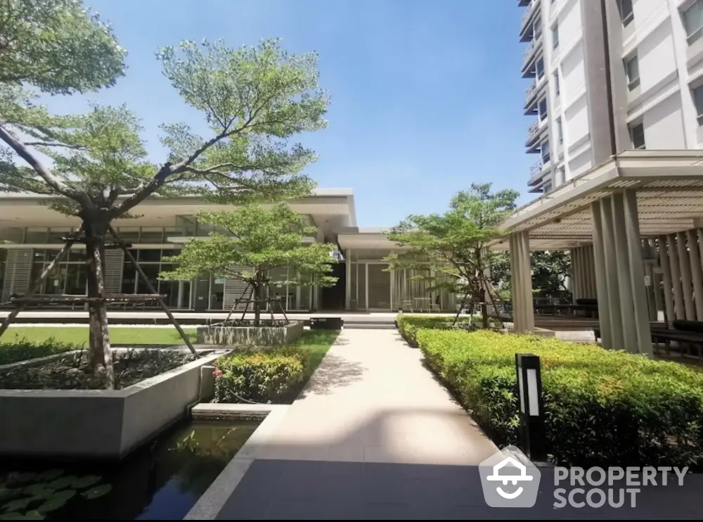 Modern apartment building with lush garden and clear blue sky