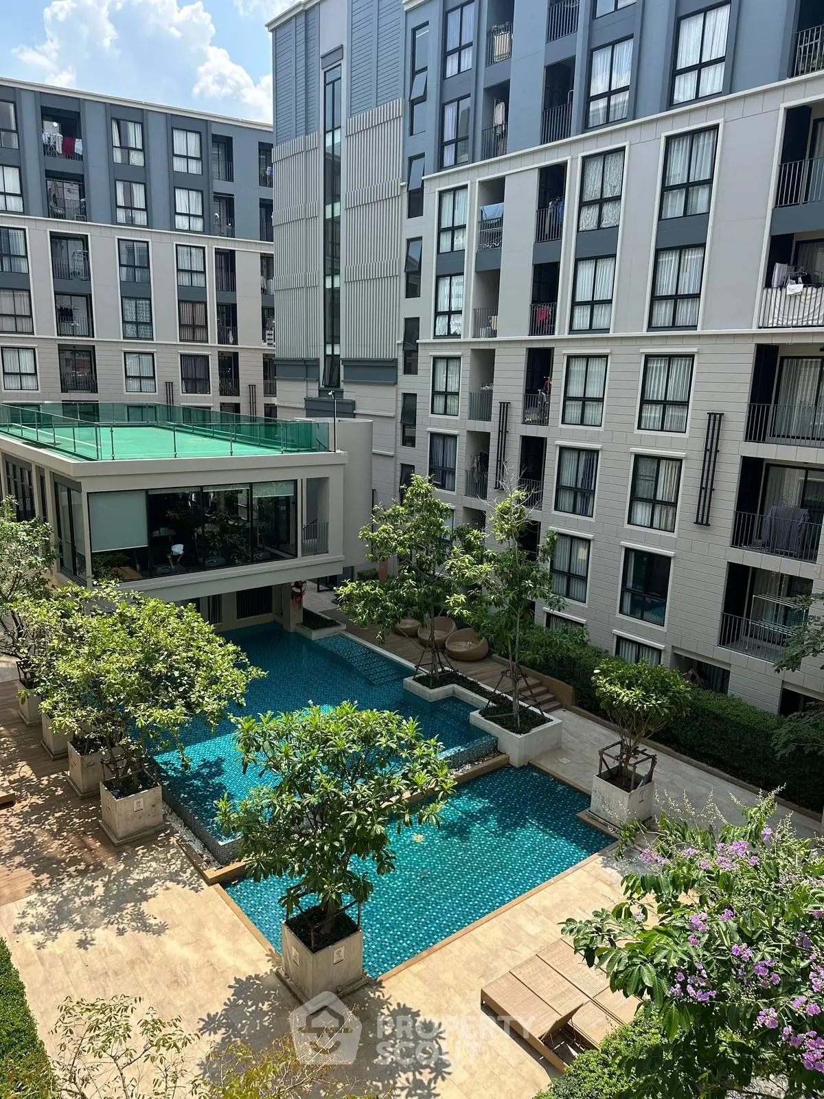 Modern apartment complex with a stunning outdoor pool and lush greenery, perfect for luxury living.