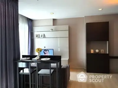 Modern kitchen with sleek white cabinetry and integrated appliances, complemented by a stylish dining area with a dark table set.