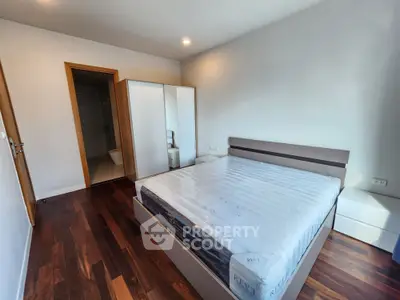 Modern bedroom with wooden flooring and sleek furniture in a contemporary apartment.