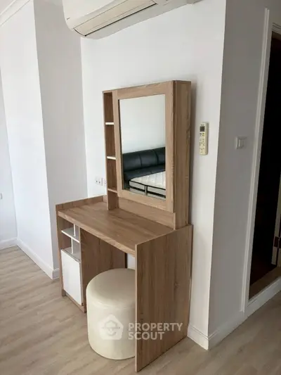 Modern bedroom with stylish wooden vanity and mirror, featuring sleek air conditioning unit.