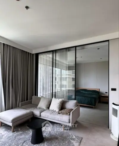 Modern living room with cozy sofa and view into stylish bedroom