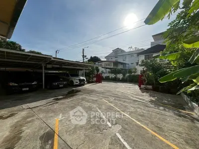 Spacious residential parking area with ample sunlight and greenery.