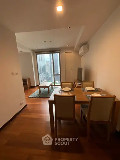 Modern apartment dining and living area with city view, featuring wooden flooring and stylish furniture.