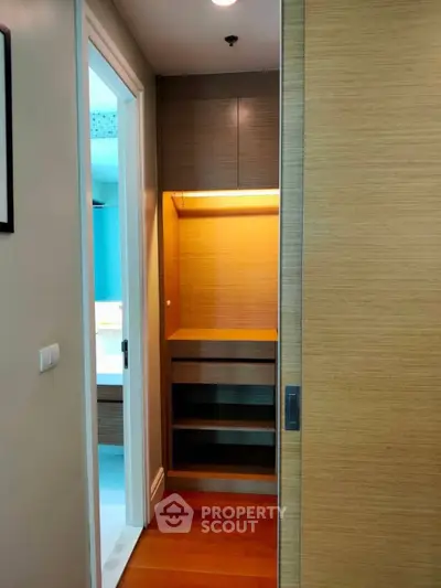 Compact storage space with wooden shelves and sliding door in modern apartment