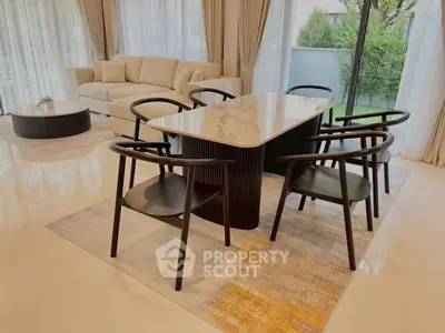 Elegant living room with modern dining set and large windows overlooking a lush garden.