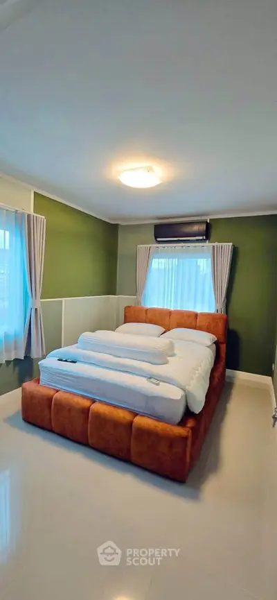 Spacious bedroom with modern decor and large windows in a stylish home.