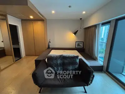 Modern bedroom with cozy seating and balcony view in urban apartment