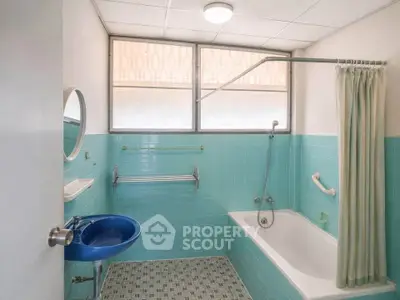 Charming vintage bathroom with blue tiles and bathtub, featuring a unique blue sink and retro design.