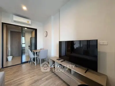 Modern living room with sleek furniture and open layout, featuring a large TV and dining area.