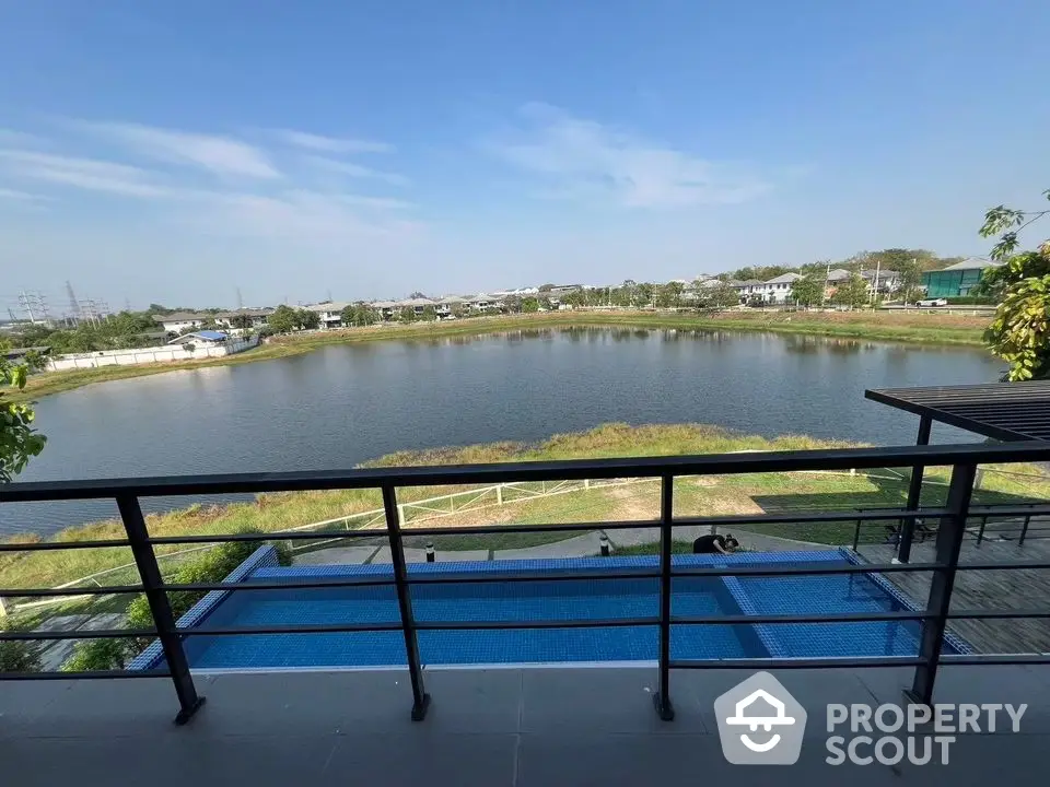 Stunning balcony view overlooking serene lake and pool in modern residential area.