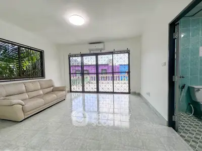 Spacious living room with large windows and modern sofa, perfect for relaxation.