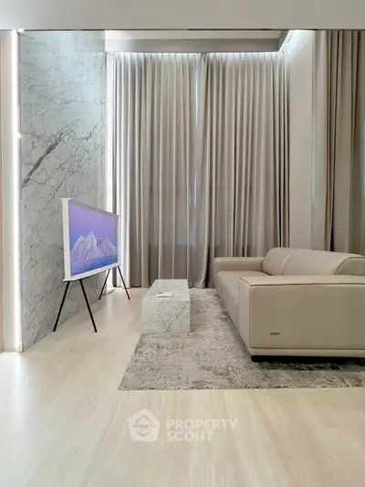 Modern living room with sleek marble accents and stylish furniture, featuring a contemporary TV setup.