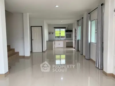 Spacious open-plan living area with modern kitchen and large windows in a bright, airy home.