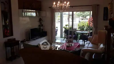 Charming living room with elegant chandelier and garden view, perfect for relaxation and entertaining.