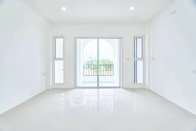 Spacious and bright living room with large windows and balcony access, perfect for modern living.