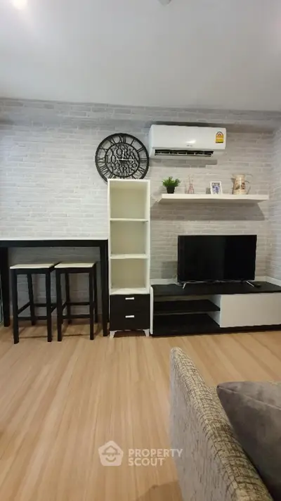 Modern living room with stylish decor and air conditioning, featuring a TV and minimalist furniture.