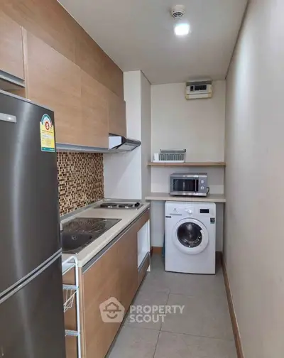 Compact kitchen with modern appliances and washing machine in cozy apartment.