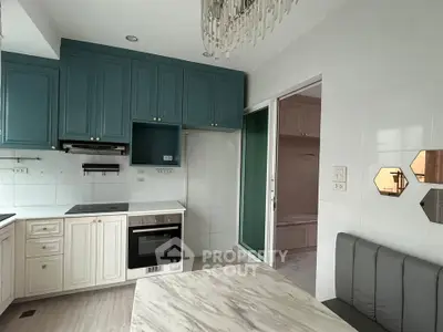 Charming kitchen with teal cabinets and modern appliances in a cozy apartment setting.