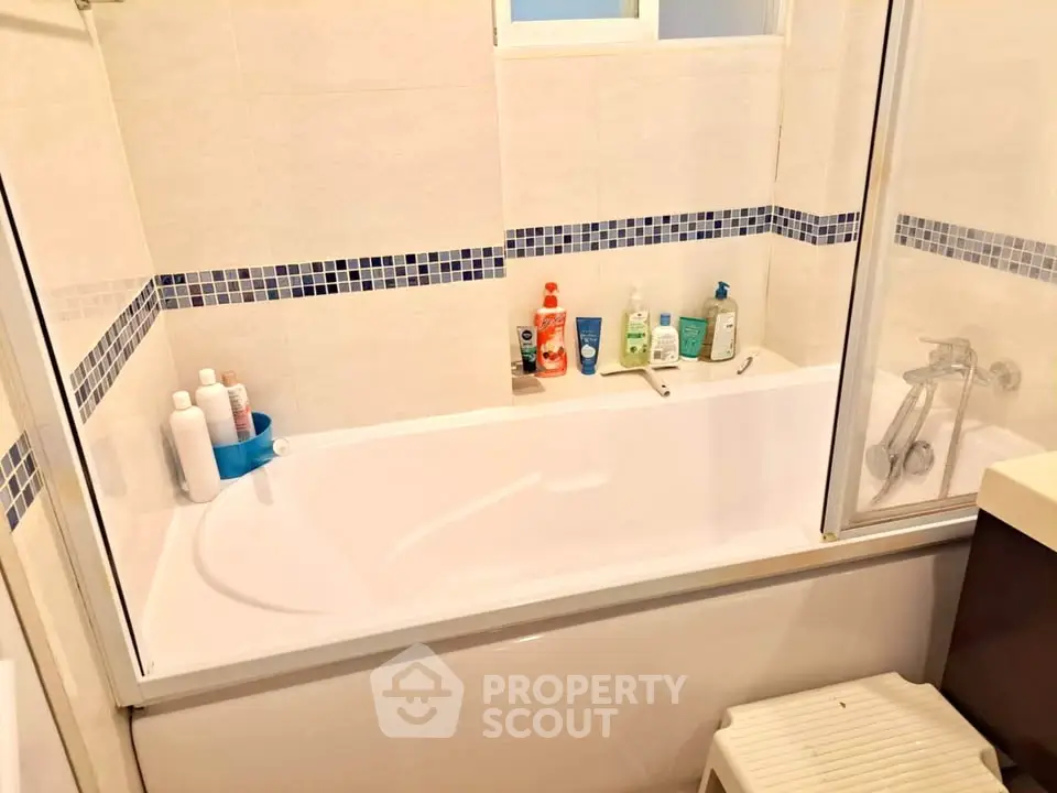 Cozy bathroom with bathtub and modern tiled design, ideal for relaxation.