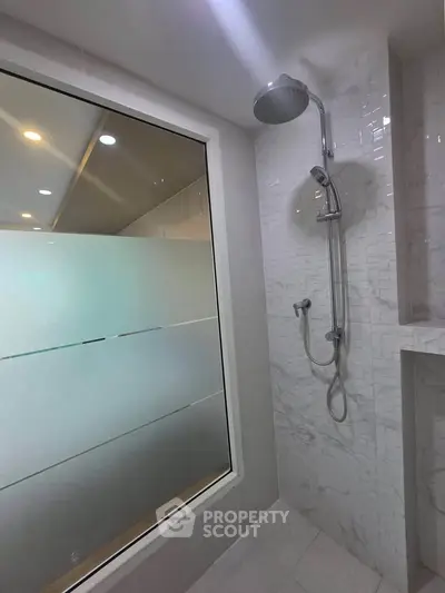 Modern bathroom with sleek shower and frosted glass window for privacy.
