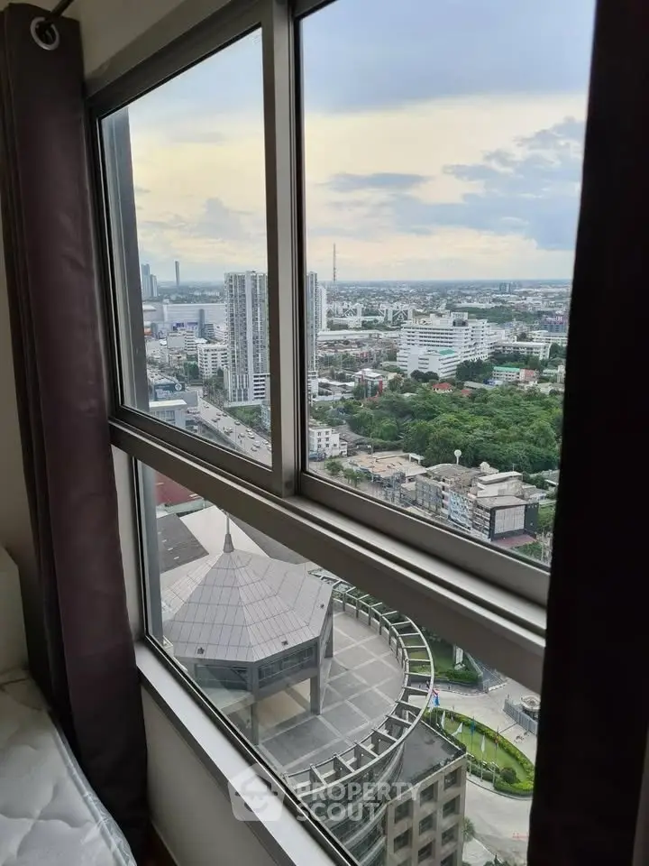 Stunning high-rise city view from a modern apartment window, showcasing urban skyline and lush greenery.