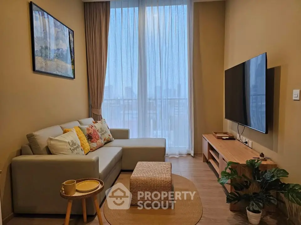 Modern living room with cozy sofa, large TV, and floor-to-ceiling windows offering city views.