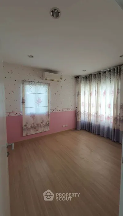Charming bedroom with wooden flooring and large windows for natural light.