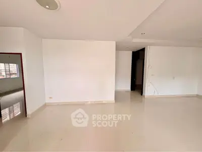 Spacious empty living room with white walls and tiled flooring, ready for customization.