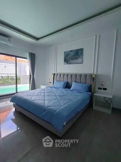 Luxurious bedroom with pool view and modern decor in a stylish home.