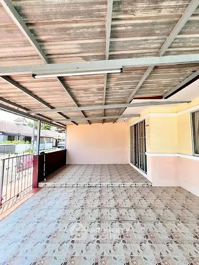 Spacious covered balcony with tiled flooring and sliding glass doors in a suburban home.